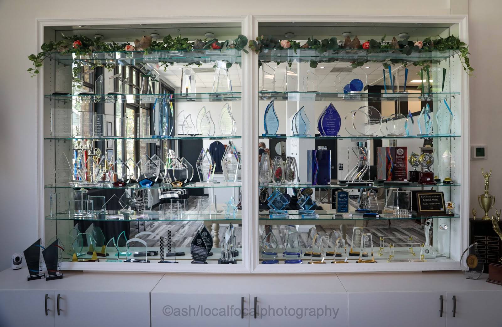 Lit glass display case filled with glass and acrylic awards